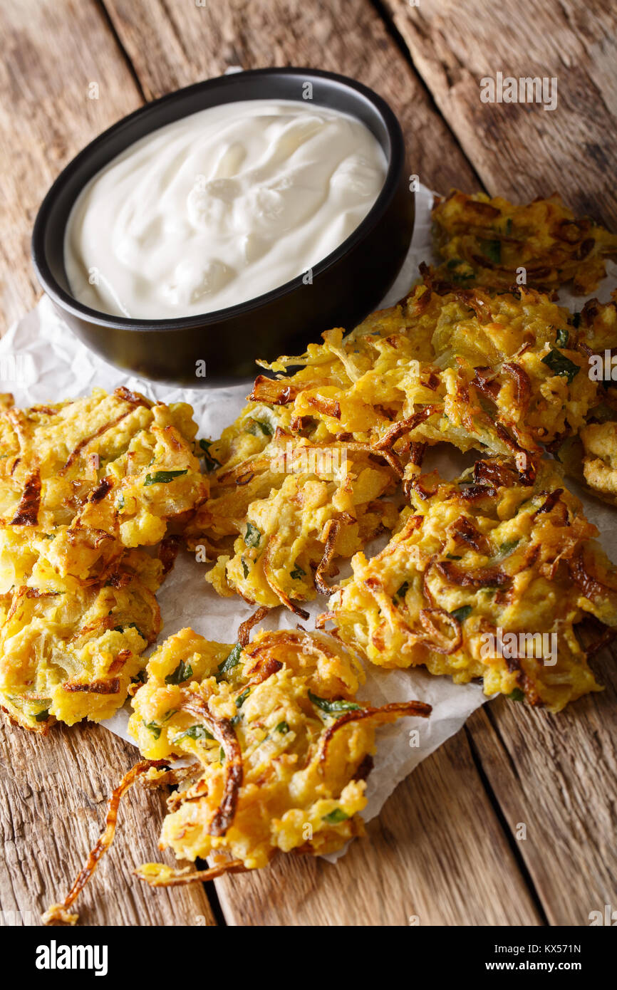 Indiano fritto croccante Bhajis di cipolla e yogurt vicino sul piano verticale. Foto Stock