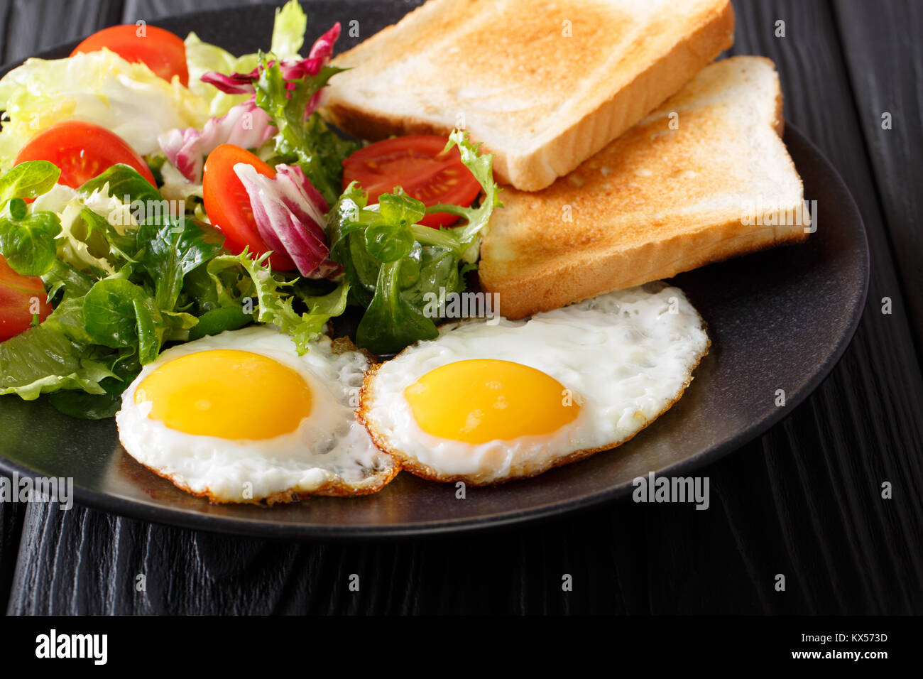 Uova fritte con verdura fresca insalata e pane tostato close-up su una piastra orizzontale. Foto Stock