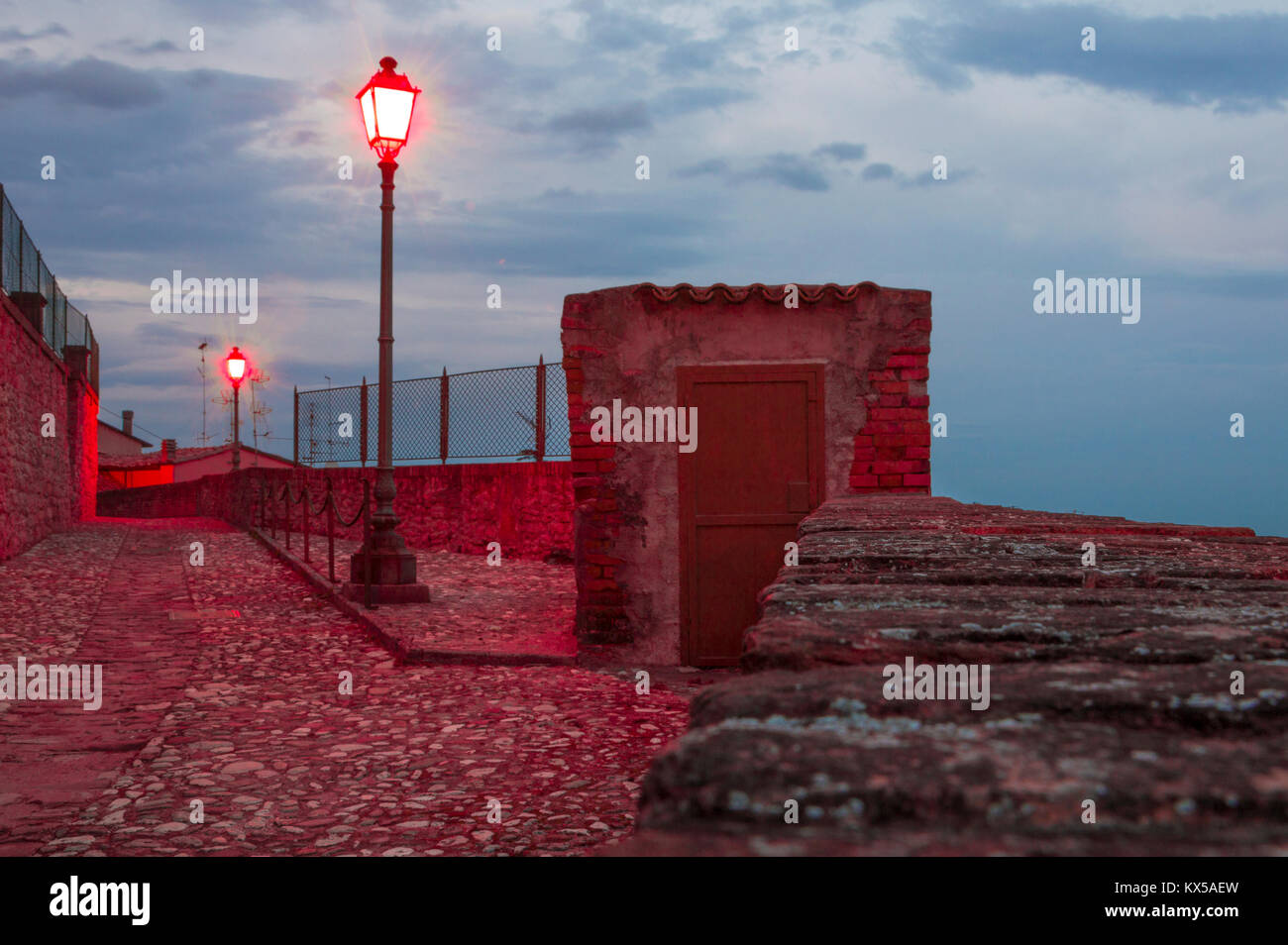 Esterni porta di legno in un vecchio posto di guardia di un muro di cinta con red le luci di strada Foto Stock