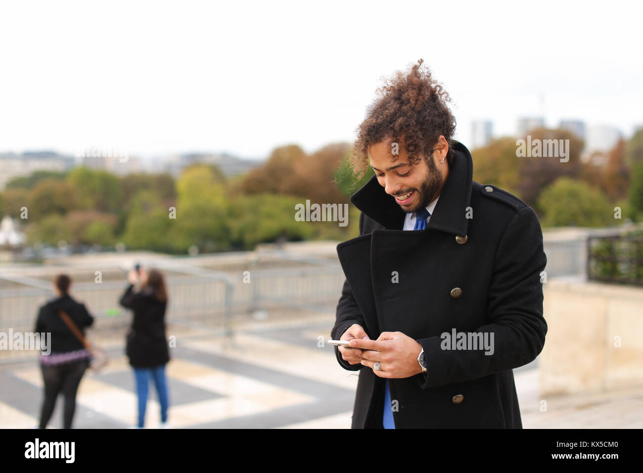 Arabian boy camminare vicino a Torre Eiffel con lo smartphone in slow mo Foto Stock