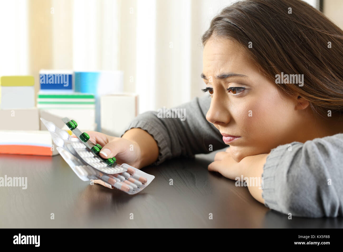 Dubbia la donna in cerca di un lotto di medicinali seduti a un tavolo a casa Foto Stock