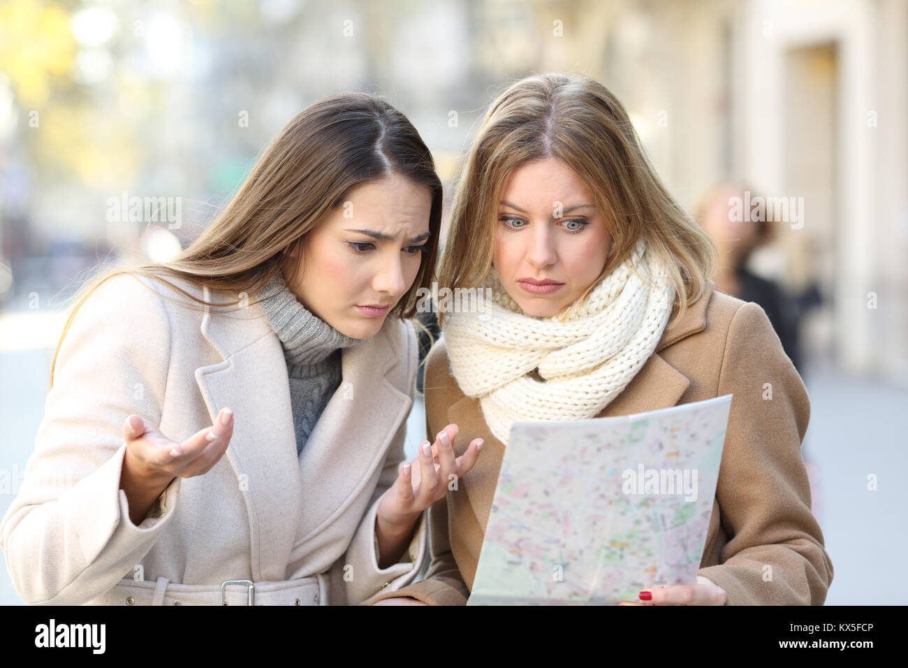 Vista frontale ritratto di due turisti persi donne alla ricerca posizione in una guida sulla strada di vacanze invernali Foto Stock