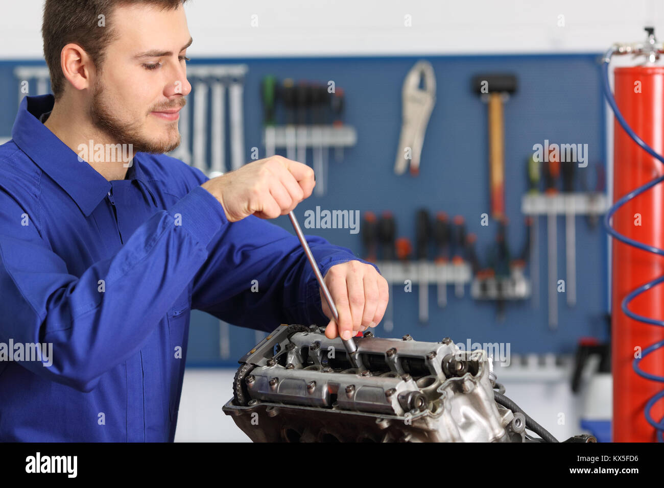 Soddisfatto meccanico la riparazione di un motore in moto in una officina meccanica Foto Stock