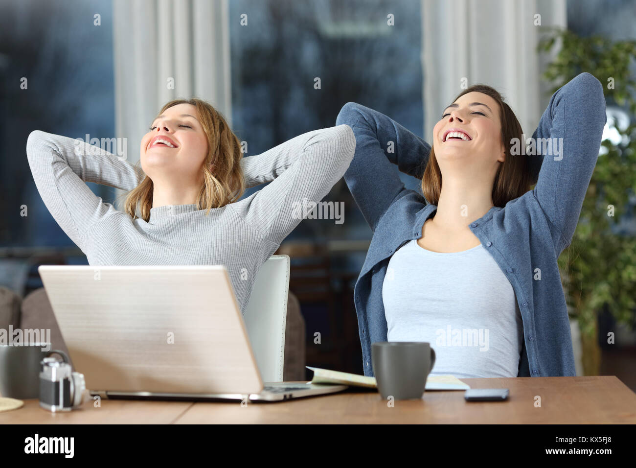 Due turisti soddisfatti le donne rilassarsi seduti sulle sdraio ad appartamento in vacanza in serata Foto Stock