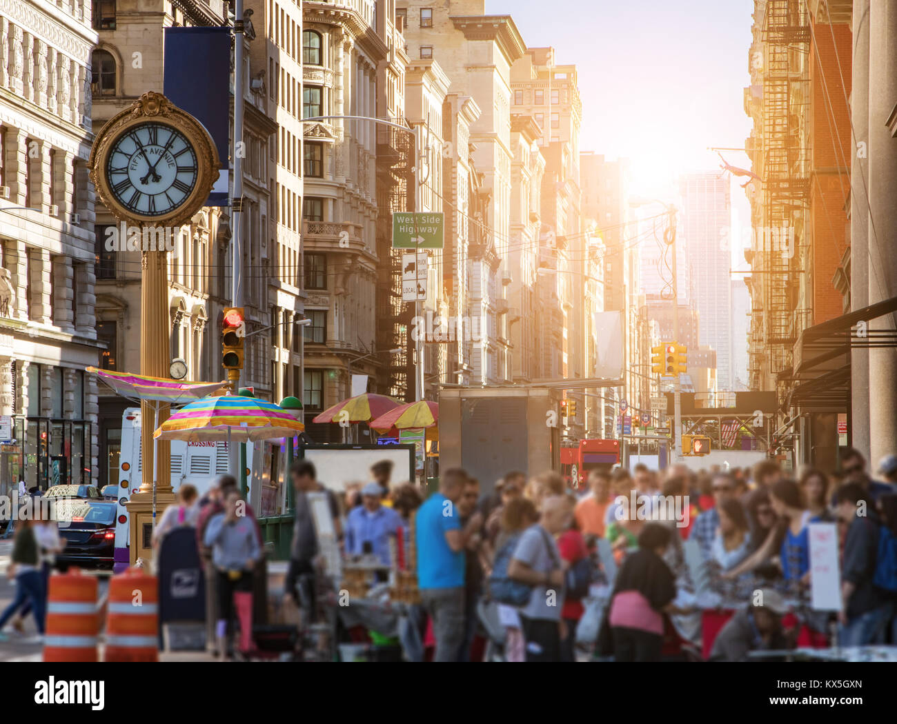 La luce del sole splende su edifici di Manhattan con una folla di gente che acquisti presso i commercianti di strada nella città di New York Foto Stock
