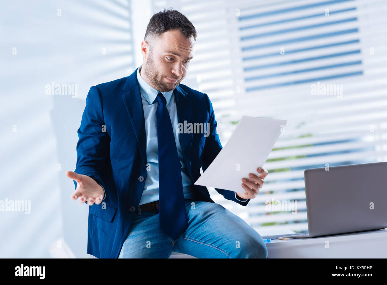 Sorpreso giovane uomo che guarda il documento senza crederci Foto Stock