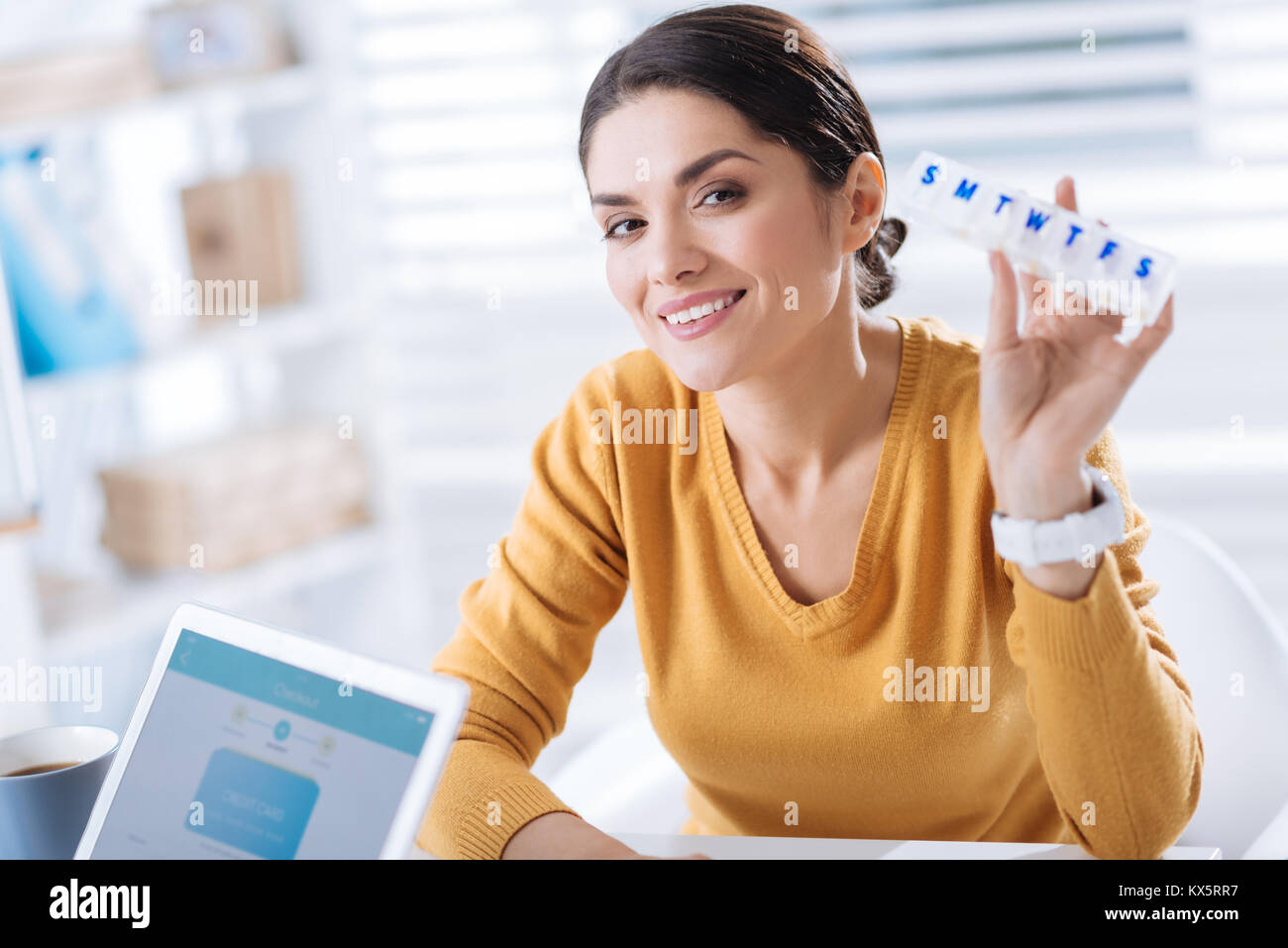 Donna sorridente tenendo un utile scatola di pillole e la sensazione di essere contento di recuperare Foto Stock