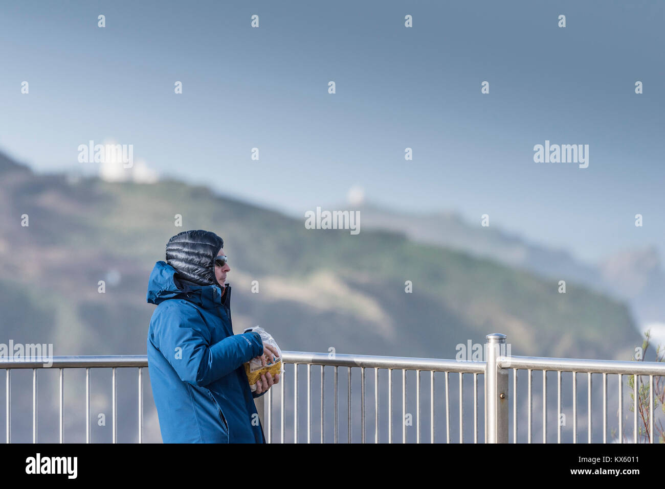 Un uomo di mangiare uno spuntino e indossando vestiti caldi contro il freddo ventoso. Foto Stock