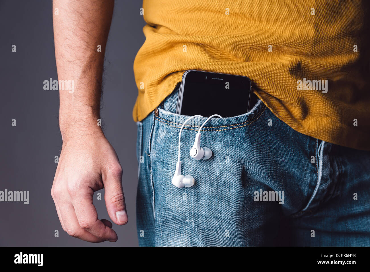 Smartphone con auricolari su un caucasian giovani maschi adulti tasca dei jeans. Foto Stock