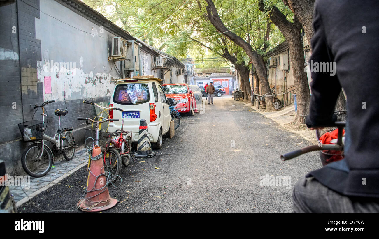 Un vicolo in cinese tradizionale houton area con auto, biciclette e persone. Pechino, Cina Foto Stock