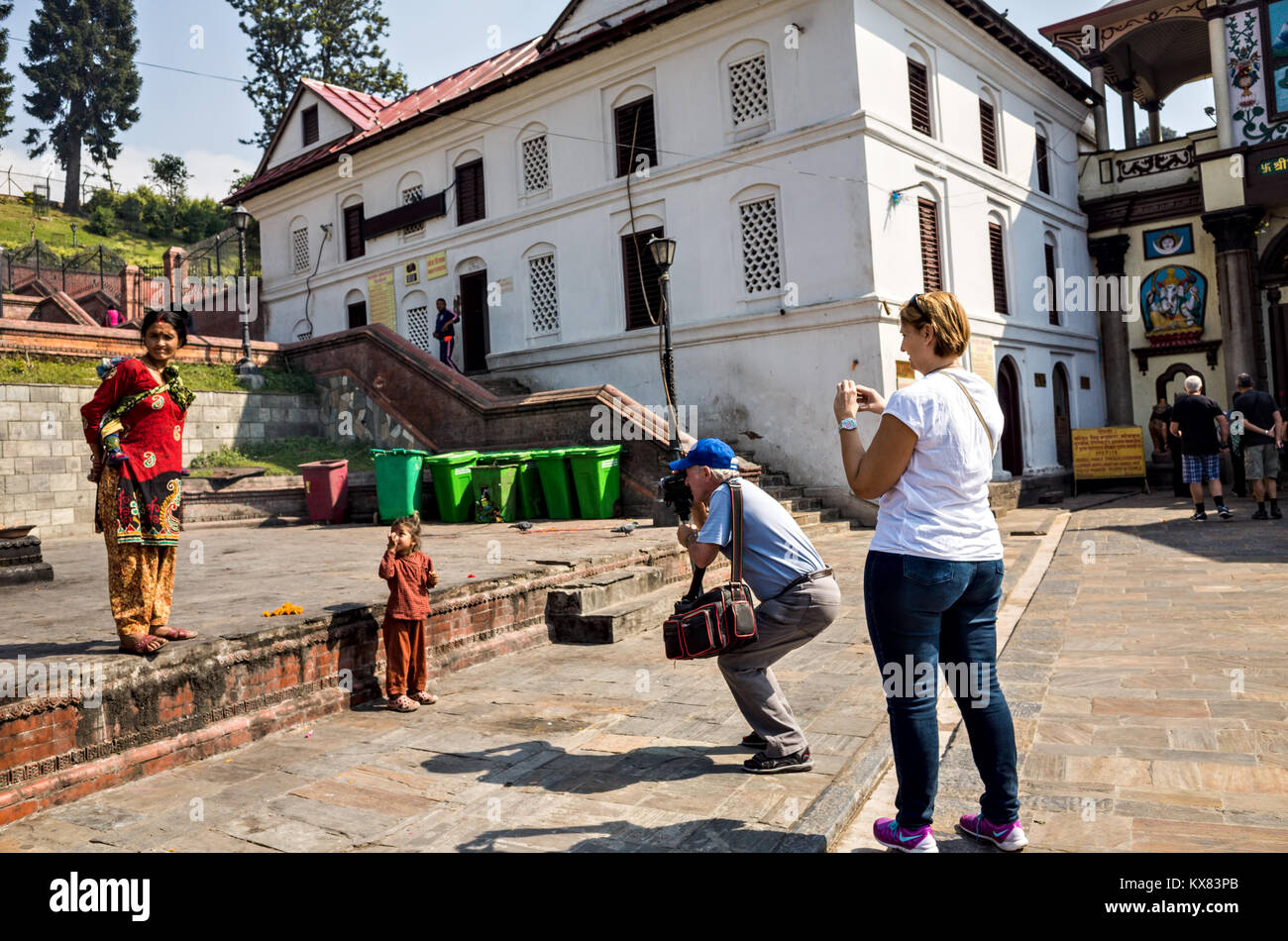 Due turisti occidentali fotografi a fotografare un 8-10 anni il bambino e sua madre al tempio di Pashupatinath complessa, Kathmandu, Nepal Foto Stock