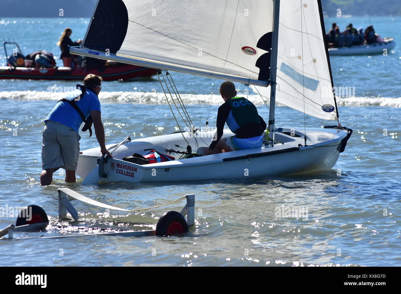 Il lancio di 420 classe dinghy a vela da rimorchio a mano in acqua poco profonda prima della gara. Foto Stock