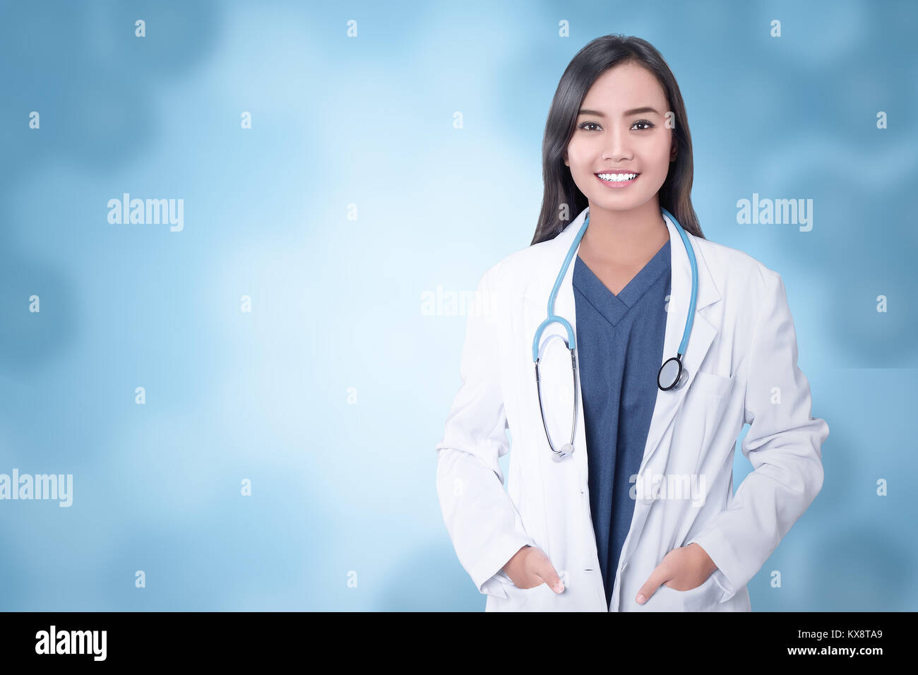 Giovani asiatici medico con le mani nella tasca del cappotto su sfondo blu Foto Stock