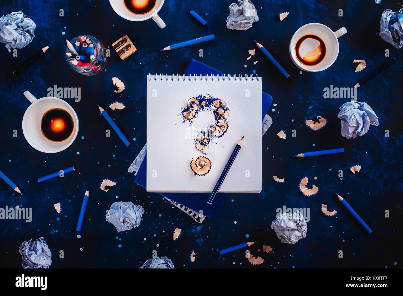 Punto interrogativo da trucioli di matita con carta sgualcita sfere, matite, taccuini e vuoto tazze da caffè. Ancora vita con lo scrittore workplace. Blocco creativo Foto Stock