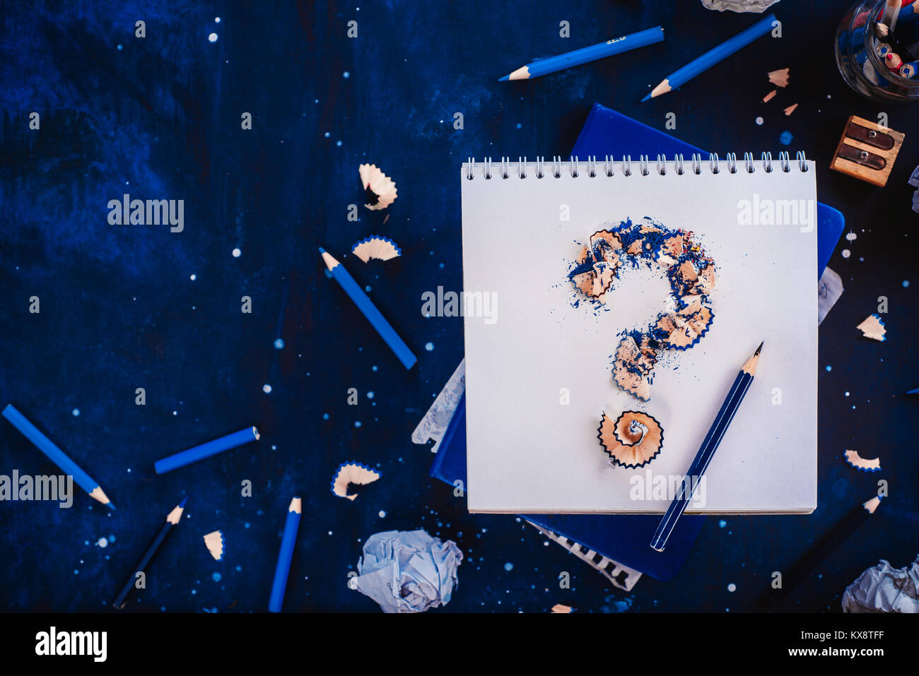 Punto interrogativo da trucioli di matita con carta sgualcita sfere, matite, taccuini e vuoto tazze da caffè. Ancora vita con lo scrittore workplace. Blocco creativo Foto Stock