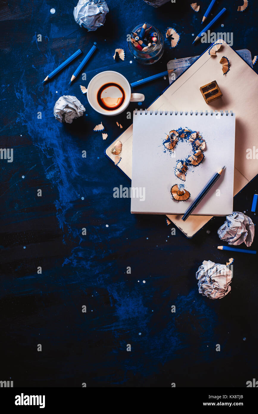 Punto interrogativo da trucioli di matita con carta sgualcita sfere, matite, taccuini e vuoto tazze da caffè. Ancora vita con lo scrittore workplace. Blocco creativo Foto Stock