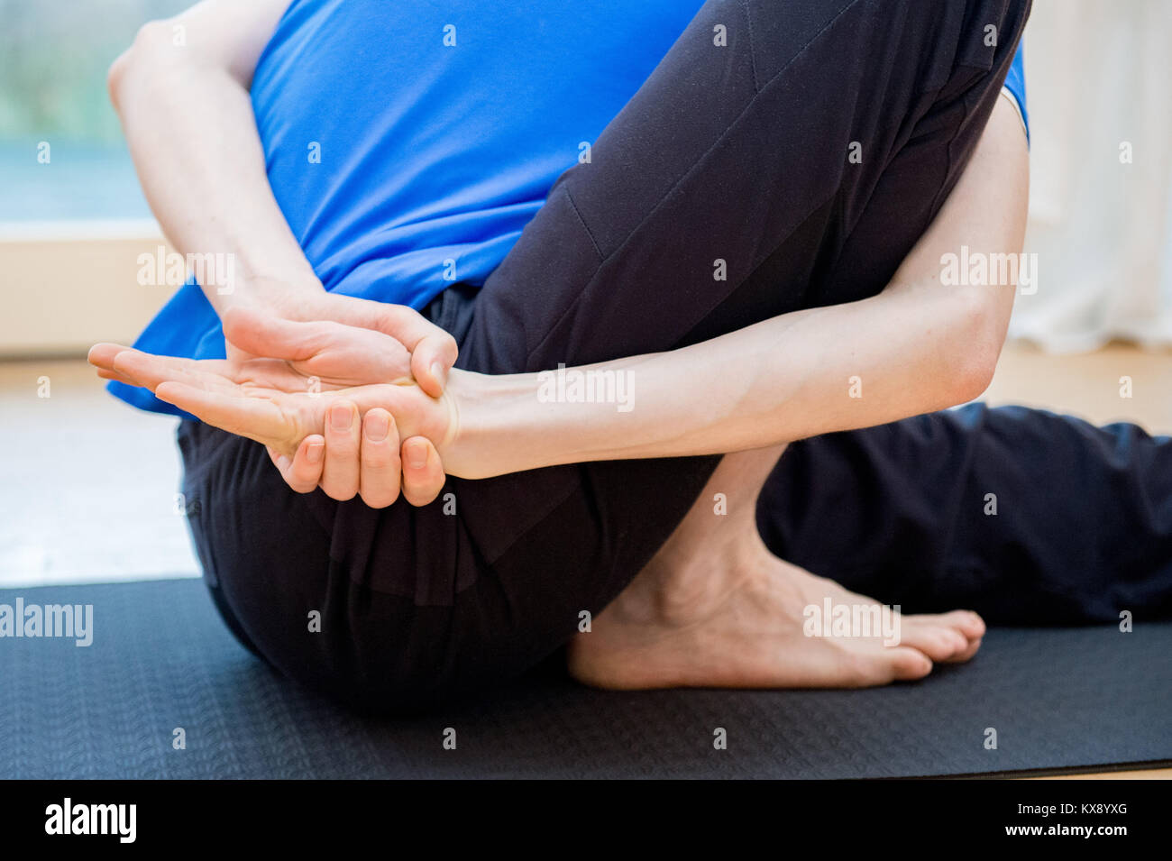 Uomo a praticare yoga al chiuso in un rifugio facendo spazio di testa a ginocchio piegare in avanti pone - Janu Sirsasana Foto Stock