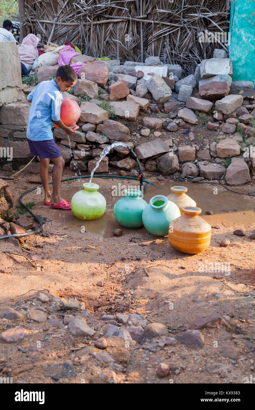 India, Karnataka, , Badami, ragazzo indiano è il riempimento di vasi d'acqua da un pubblico acqua Foto Stock