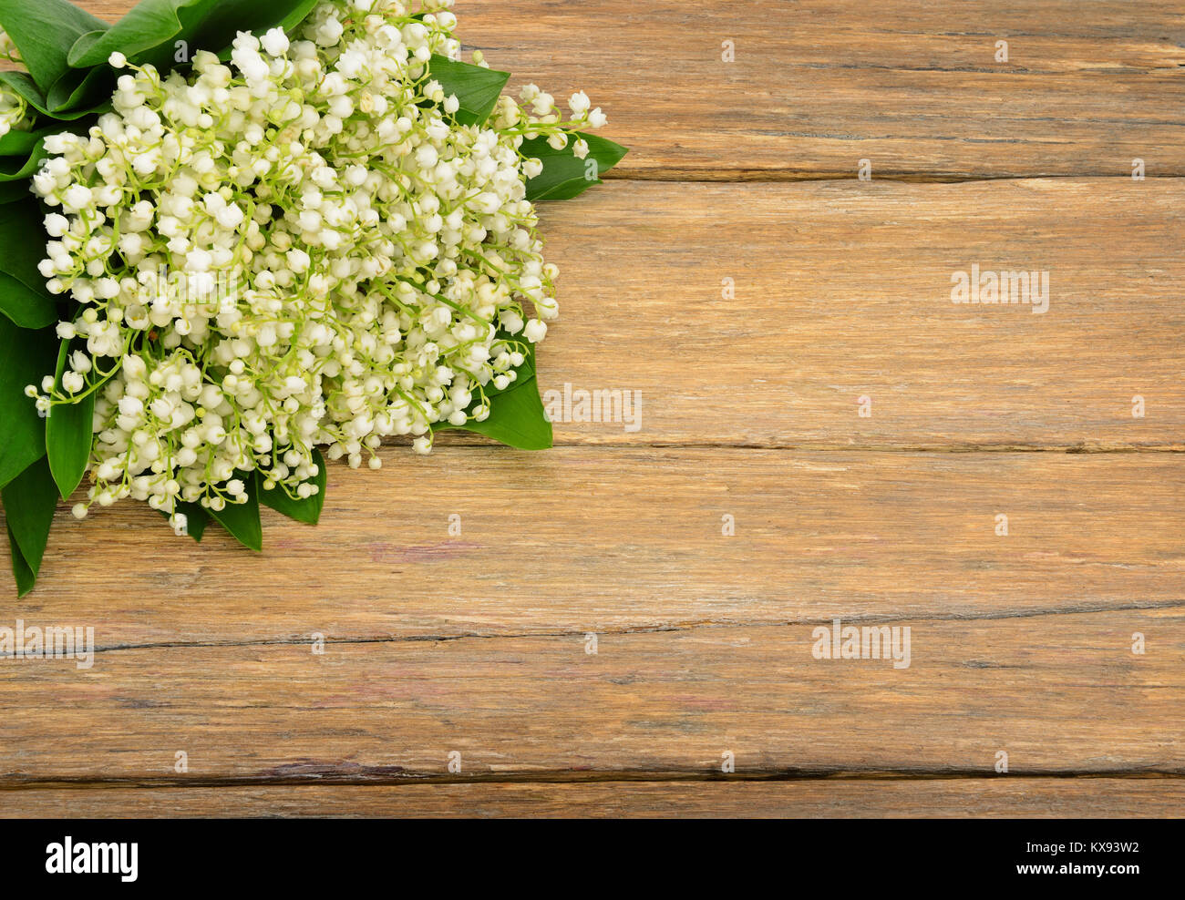 Bouquet giglio della valle sul tavolo di legno. Fiori di primavera sulla vecchia sullo sfondo di legno. Vista dall'alto. Copia dello spazio per il tuo testo. Foto Stock