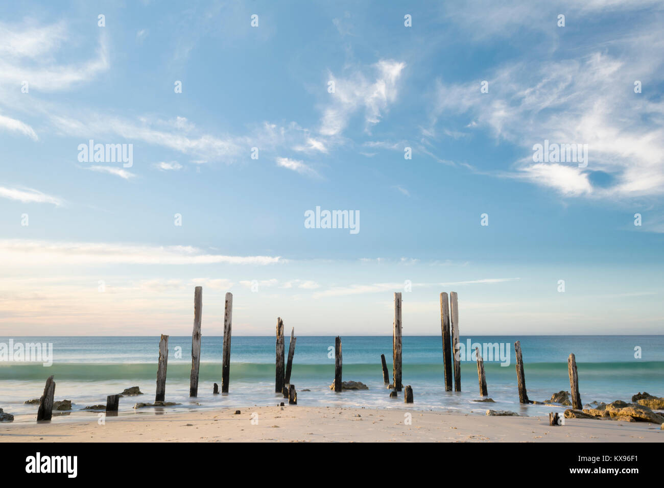 Porto Willunga Beach con il molo iconico rovine nella luce del giorno con una lenta velocità di otturatore accentuando la lunga ondata di rotolamento in arrivo. Trova i Foto Stock