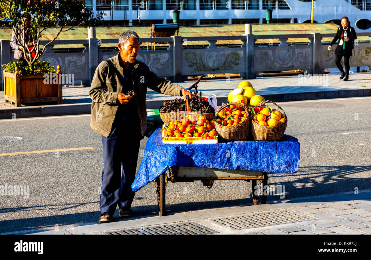 Uomo che spera di vendere frutta per i passeggeri di crociera sul Fiume Yangtze barca come essi ritorno dalla diga delle Tre Gole Foto Stock