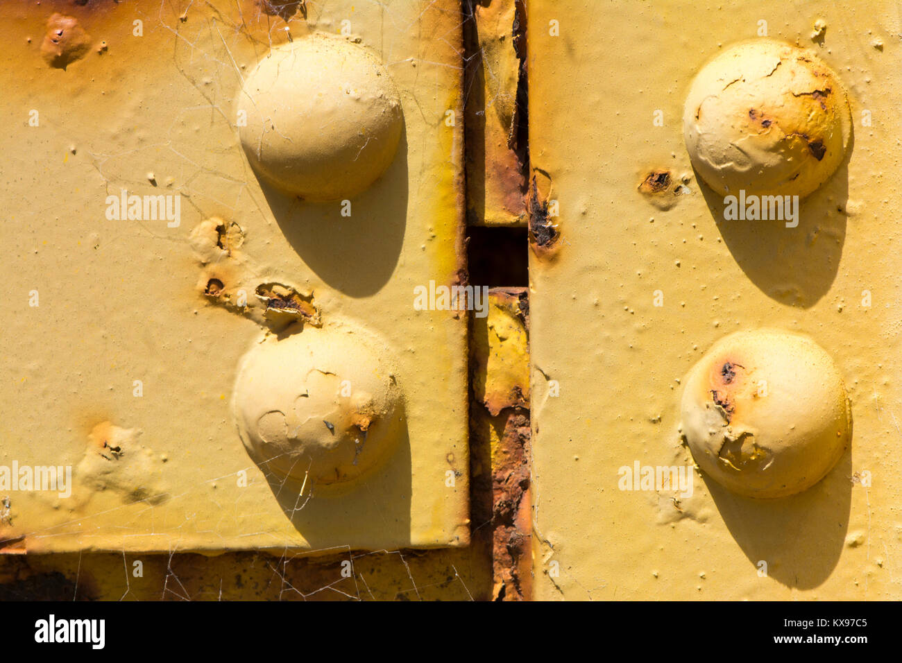 Texture astratte e forme: Invecchiamento metallo e bulloni su un pezzo di invecchiamento dei macchinari. Completare con la formazione di ruggine e la formazione di bolle, corrosione di vernice gialla. Foto Stock