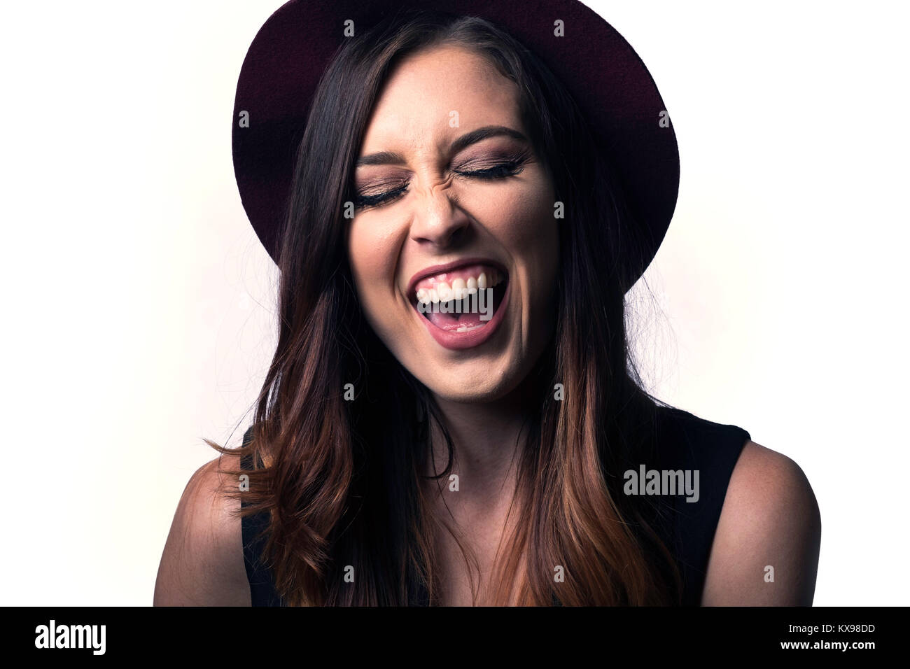 Giovane donna in hat ridere giocando su sfondo bianco Foto Stock