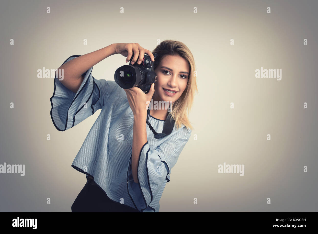 Allegro giovane donna fare foto sulla fotocamera su sfondo grigio Foto Stock