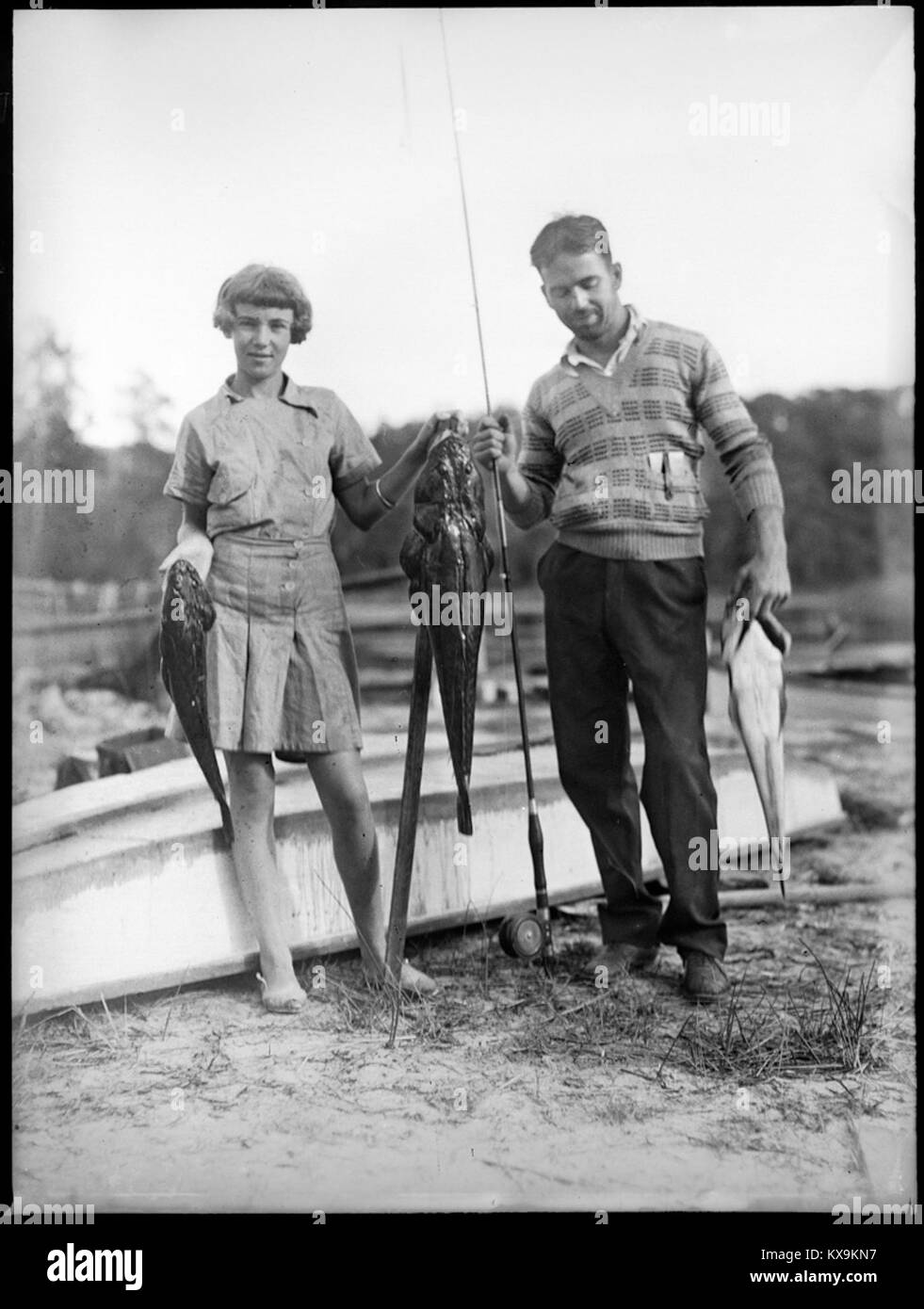 Una fotografia che mostra un uomo e una ragazza che presentano le loro catture di pesca al lago Conjola, illustrando la pesca ricreativa e le attività locali all'aperto. Foto Stock