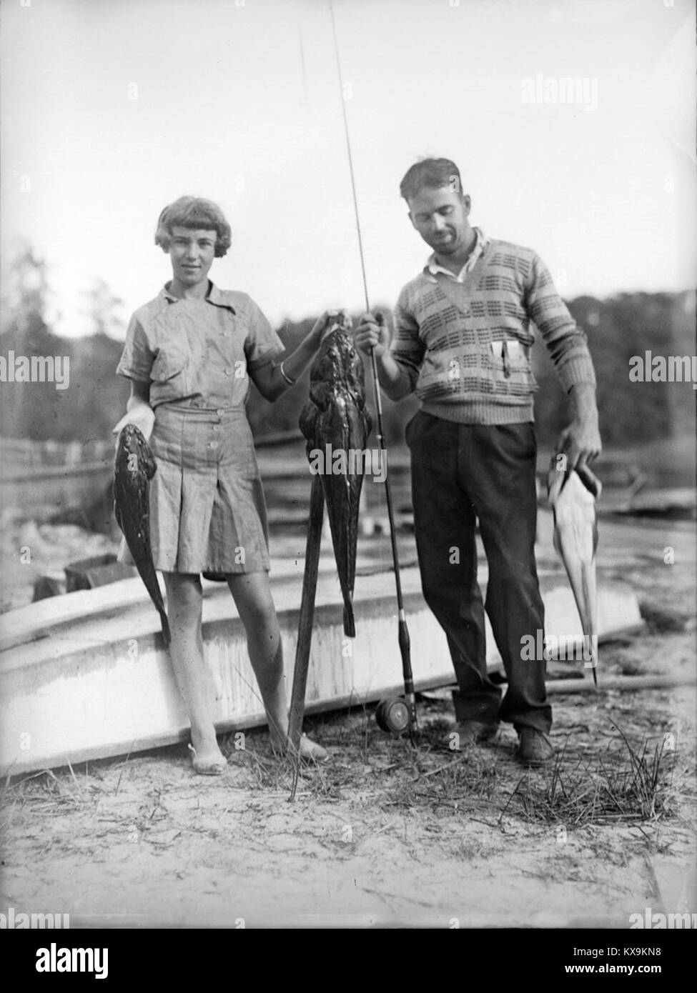 Questa fotografia, esposta al Powerhouse Museum, mostra un uomo e una ragazza che tengono la pesca al lago Conjola, offrendo un'istantanea delle attività ricreative all'aperto e della cultura della pesca. Foto Stock