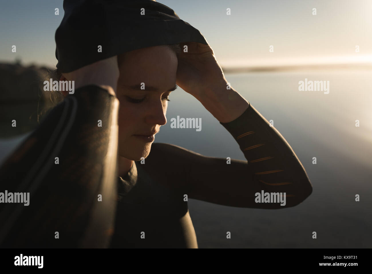 La donna è ora di prepararsi a nuotare nell'oceano al tramonto Foto Stock