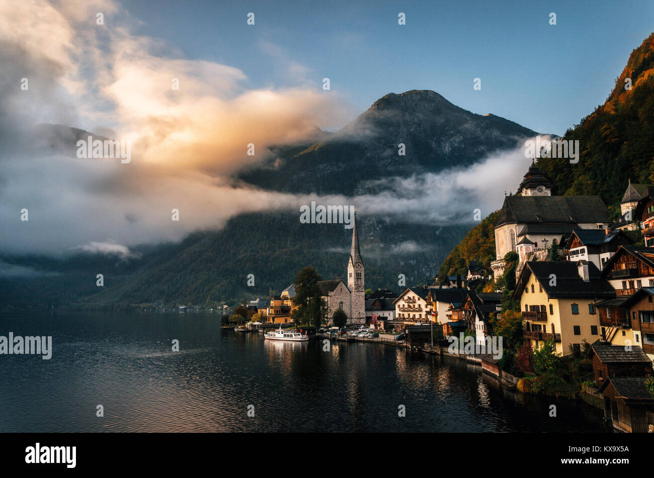 Vista panoramica del famoso Hallstatt lakeside town riflettente nel lago Hallstattersee nelle Alpi austriache nella luce del mattino con nubi luminose, Salzkammergu Foto Stock