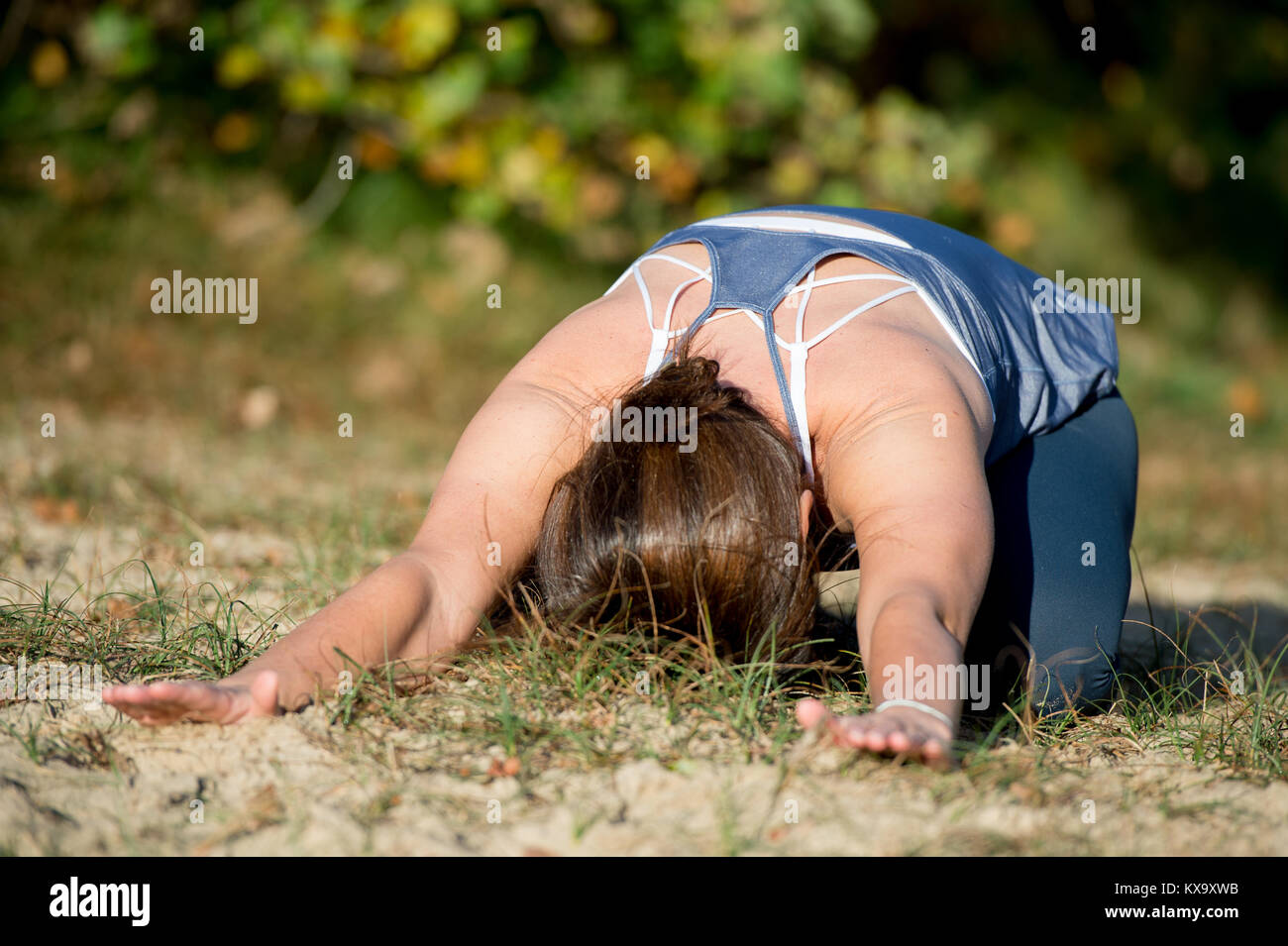 La donna a praticare yoga nella sabbia - Bambino pongono - Balasana - giorni di autunno Foto Stock