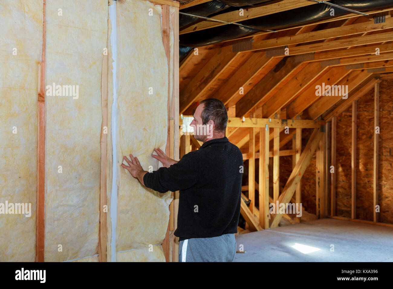 Lavoratore isolante termicamente una soffitta della casa utilizzando la lana minerale installazione di isolamento in casa isolamento della casa Foto Stock