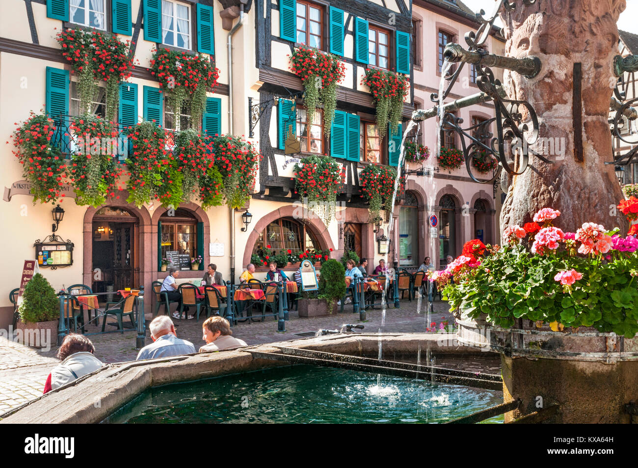 Kaysersberg Alfresco Bar Ristorante Alsace Francia fontana nella piazza centrale con ristorante Hotel Du Chateau dietro Kaysersberg Alsace Francia Foto Stock