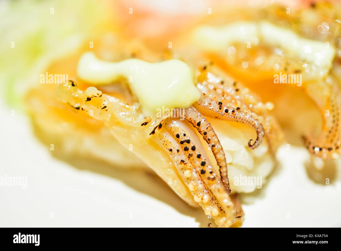 Close-up di un pezzo di sushi e rabboccato con calamari cotti. Più un piccolo tocco di maionese sulla parte superiore. Foto Stock