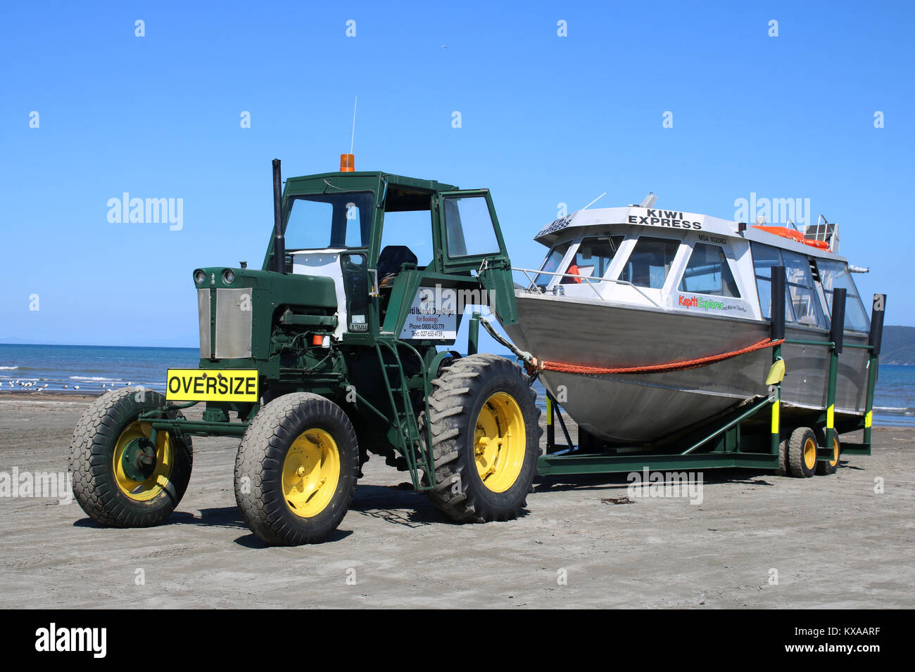 Il trattore e il noleggio barca sul rimorchio su Paraparaumu Beach, Isola del nord, Nuova Zelanda pronto a prendere i passeggeri di Kapiti Island su gite di un giorno. Foto Stock