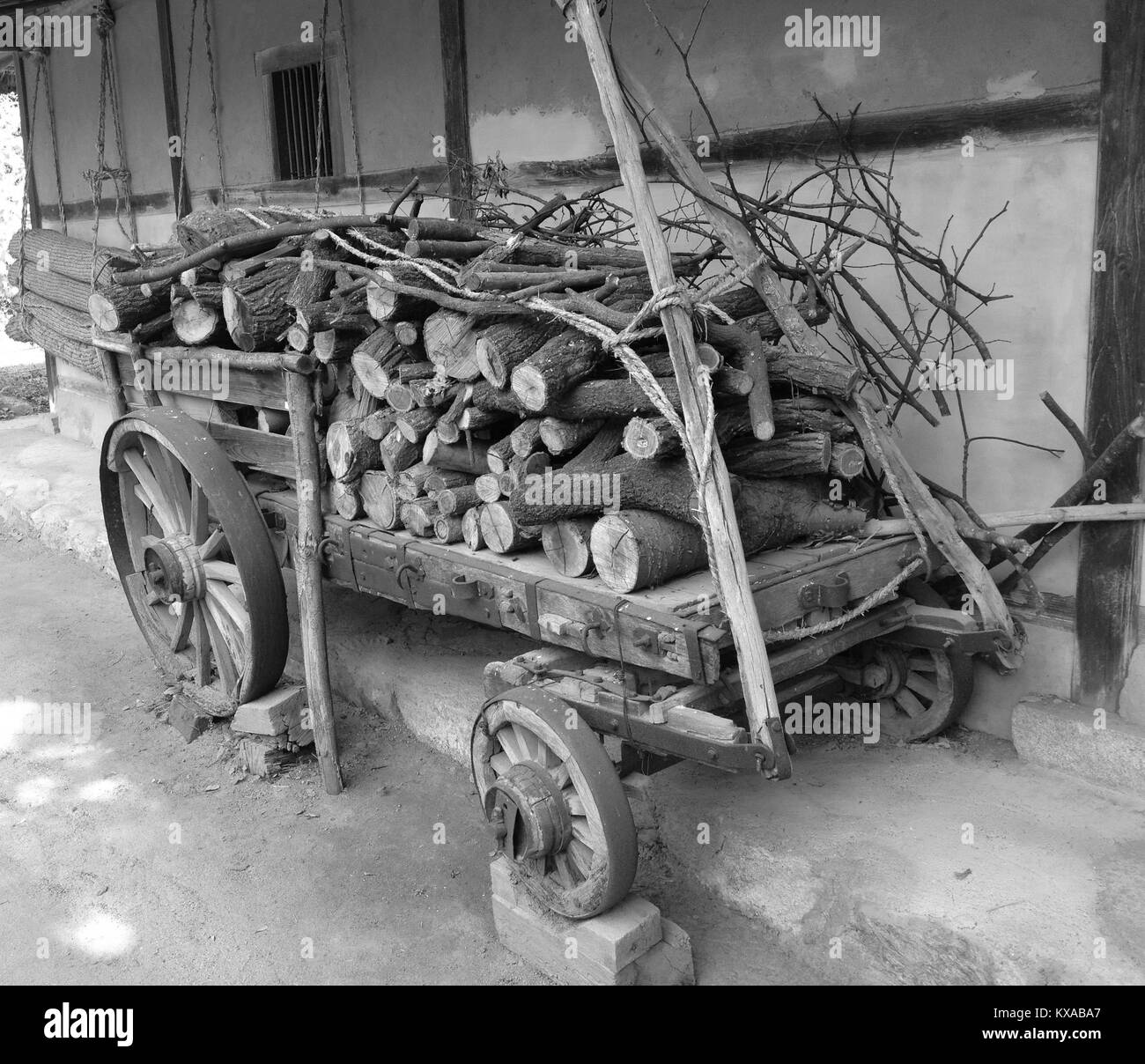 Un vecchio carrello di legno riempita con un trito di legno, contro un vecchio muro con appesi i tappetini di riso in bianco e nero, in Seoul, Corea del Sud Foto Stock