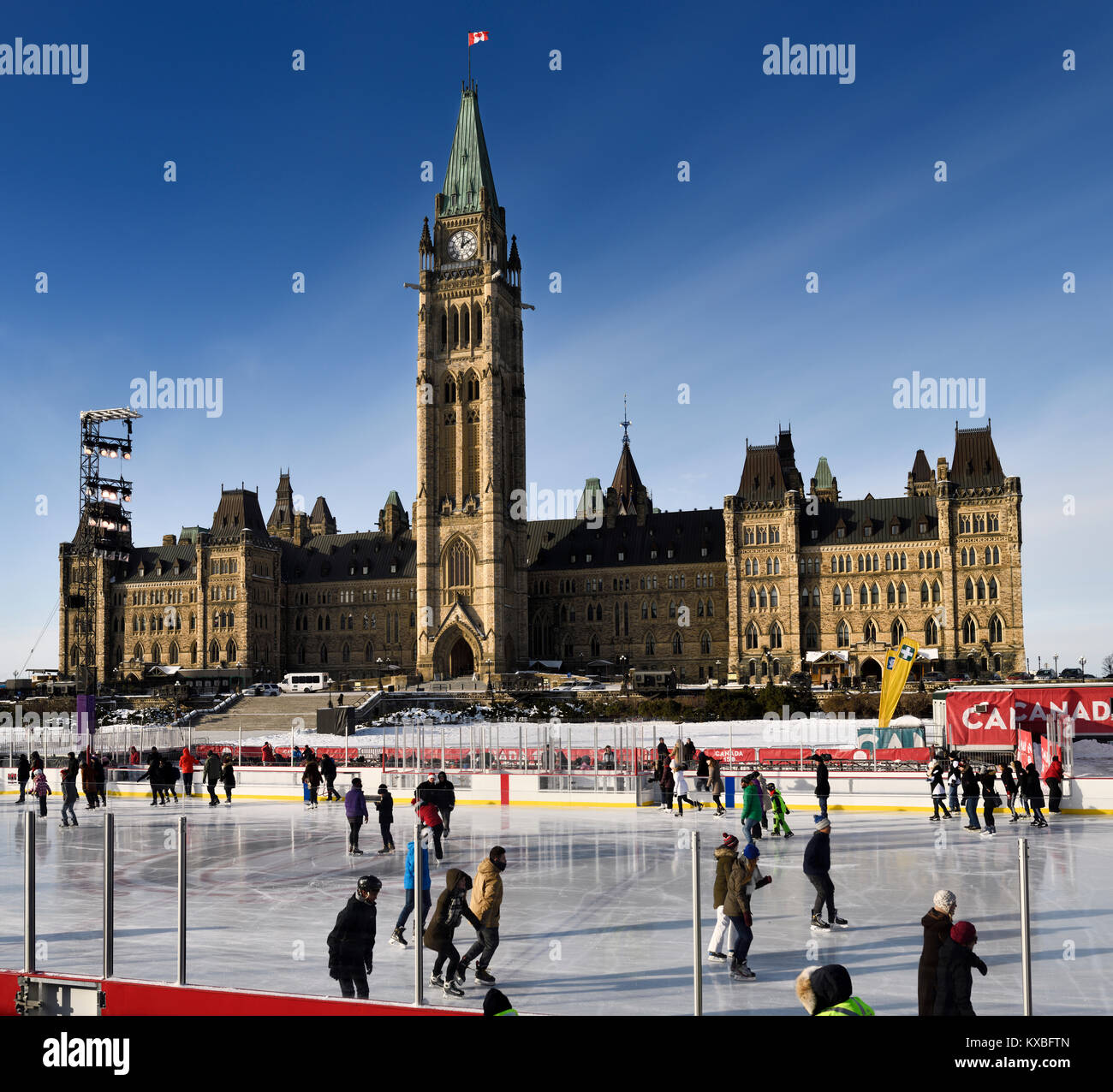 Parliament Hill blocco centrale la pace di torre con sole del pomeriggio su pattinatori sul Canada 150 Rink all aperto in inverno Ottawa Foto Stock