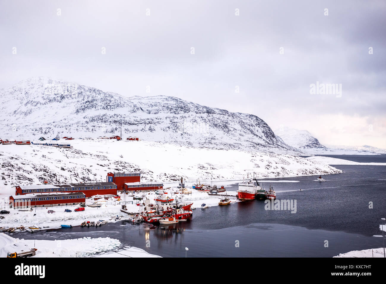 Barche da pesca e gli edifici del porto con le montagne sullo sfondo, porto di Nuuk, Groenlandia Foto Stock