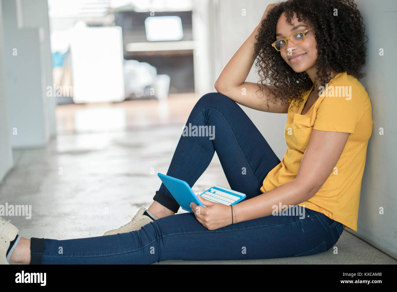 Giovane donna posa sul pavimento con il computer portatile Foto Stock