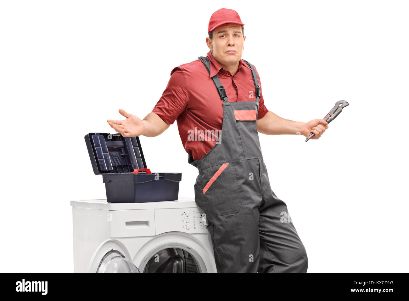 Incerto aggiustatore con una chiave appoggiata ad una macchina di lavaggio e di gesti con le mani isolati su sfondo bianco Foto Stock