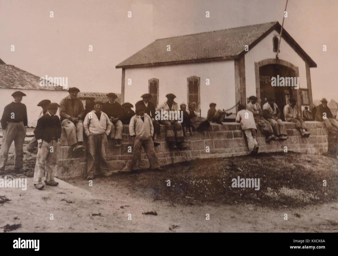 Una fotografia storica che mostra sei marinai di Kérity in piedi di fronte al rifugio delle scialuppe di salvataggio. L'immagine documenta la vita marittima e le infrastrutture di salvataggio nella regione costiera francese. Foto Stock