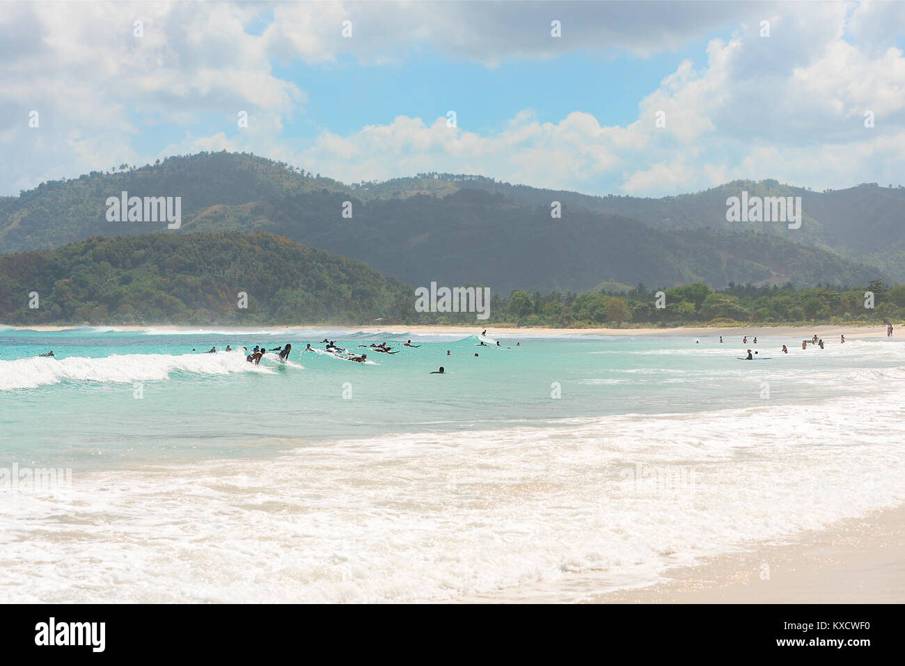 Un folto gruppo di turisti imparare a navigare su piccole onde principiante in un paradiso tropicale, Spiaggia di Kuta Lombok, Indonesia. Foto Stock