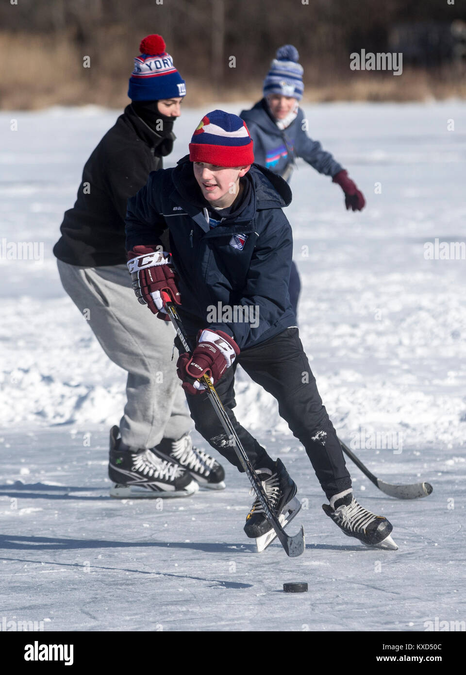 Ragazzi che giocano a hockey su ghiaccio su uno stagno ghiacciato in una giornata fredda Foto Stock