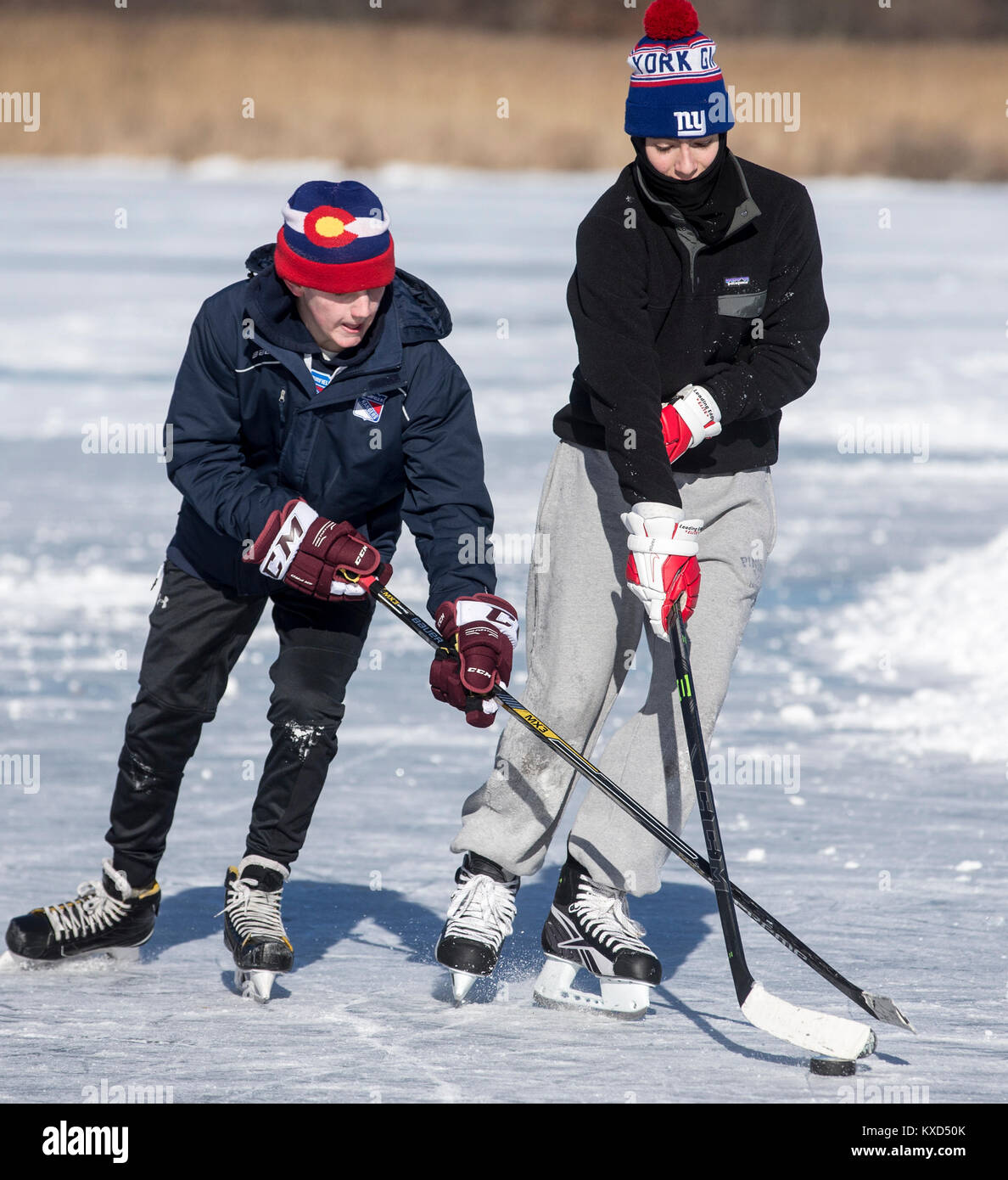 Ragazzi che giocano a hockey su ghiaccio su uno stagno ghiacciato in una giornata fredda Foto Stock