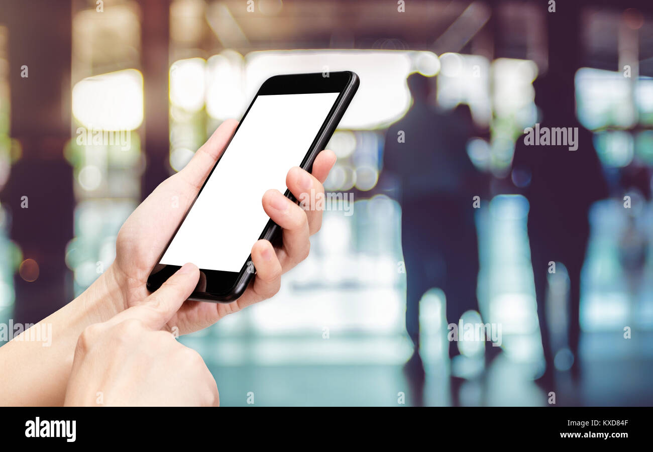 Mano fare clic su telefono cellulare con blur banca contatore al corridoio modo hall sfondo bokeh,luce schermata bianca mock up modello per aggiunta di un vostro disegno o si Foto Stock