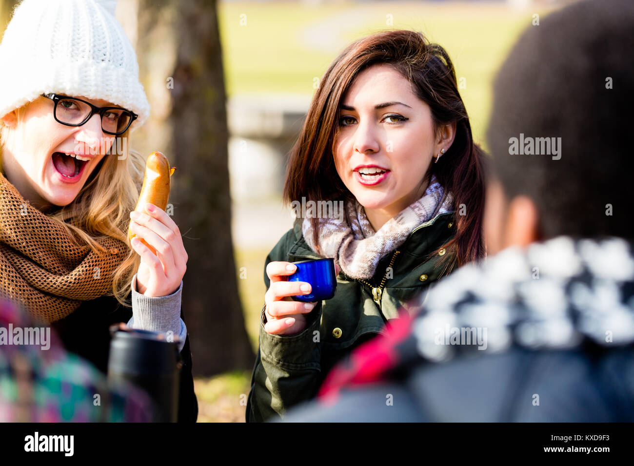 Giovani amici di sesso femminile di bere una bevanda calda all'aperto in inverno Foto Stock
