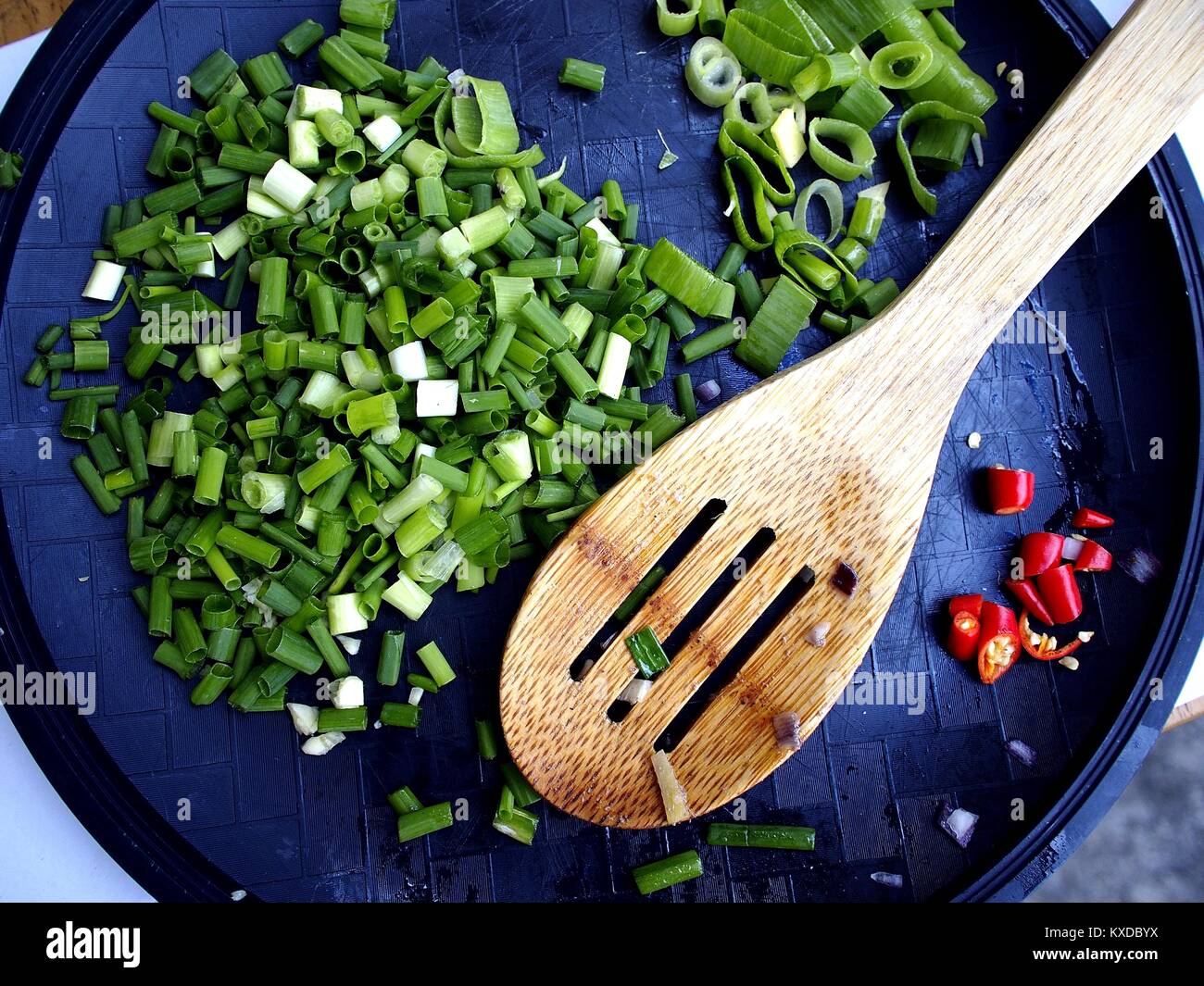 Foto di trito di cipollotto tritato e il peperoncino rosso e un cucchiaio di legno Foto Stock