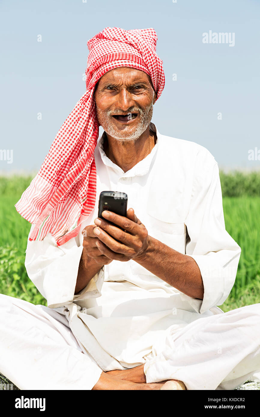 1 L'agricoltore indiano Senior uomo seduto Farm Invio telefonico di messaggistica Foto Stock